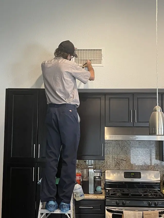 Technician inspecting an air vent during HVAC service in Melbourne